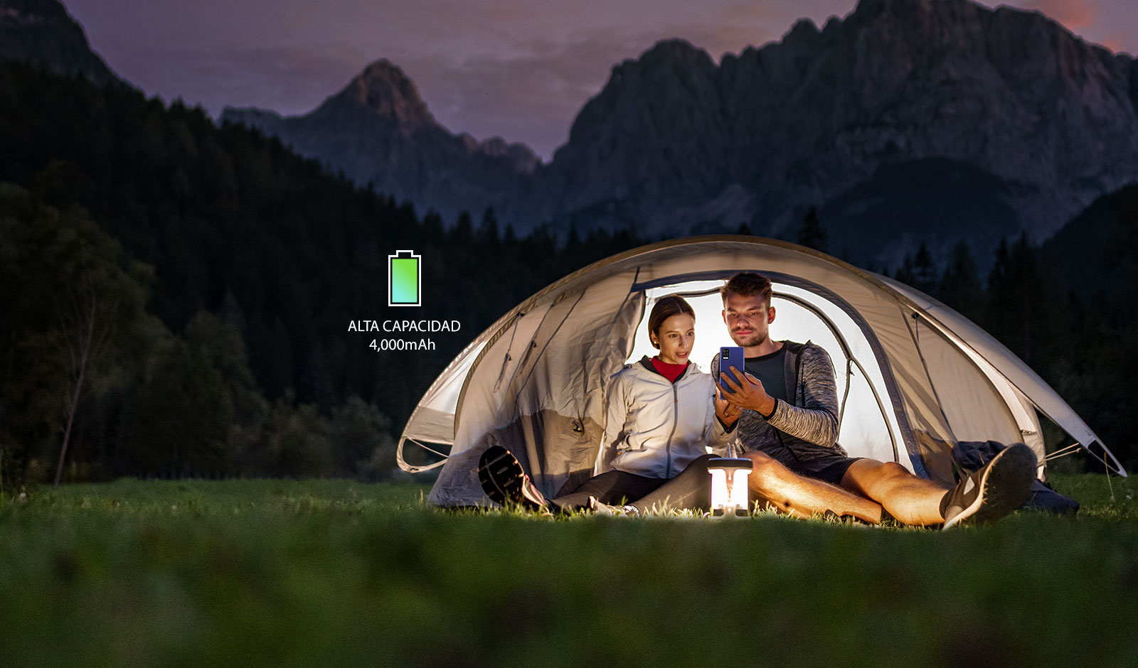 Un hombre y una mujer mirando un smartphone en una carpa en una noche oscura.