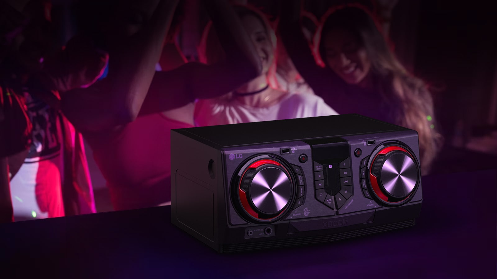 La imagen muestra un fondo borroso que representa una escena de fiesta. Delante del fondo, hay una mesa negra con un receptor colocado encima.