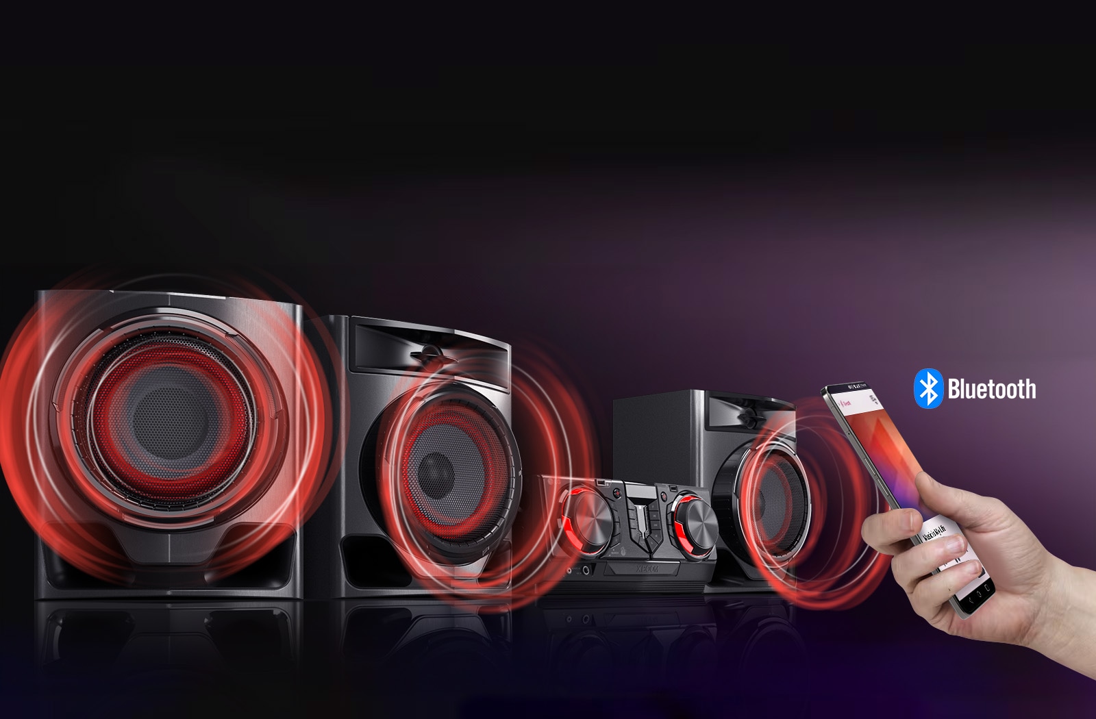La imagen muestra un fondo borroso. A la izquierda, el sistema CJ45 está colocado en un ángulo de 45 grados sobre una superficie reflectante negra. Para ilustrar el potente sonido, los gráficos de sonido circulares rojos emanan de los tres woofers. A la derecha, una mano sostiene un teléfono inteligente.