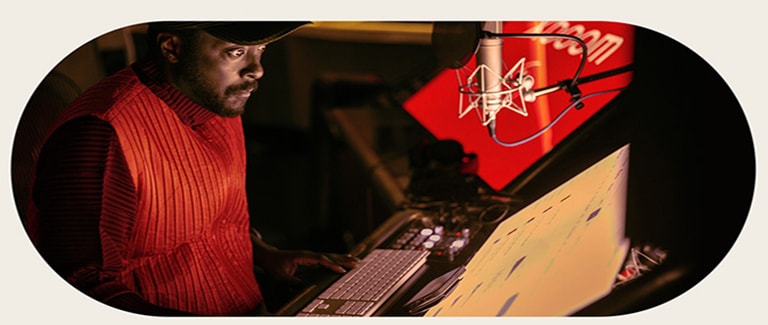 will.i.am está trabajando en el estudio mirando una pantalla colocada debajo de un micrófono.
