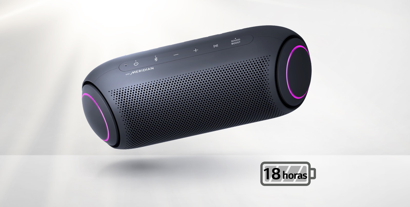 El LG XBOOM Go se inclina hacia la izquierda y flota en el aire. La iluminación del woofer es magenta.