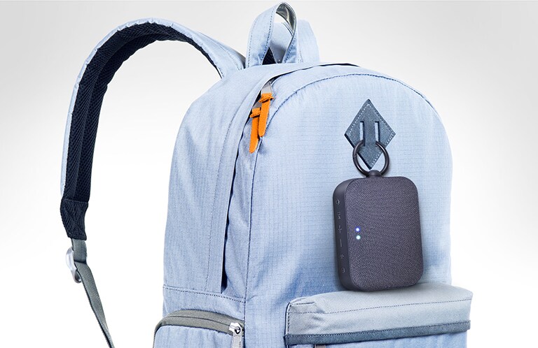 LG XBOOM Go PM1 está enganchado a la mochila de color azul celeste.
