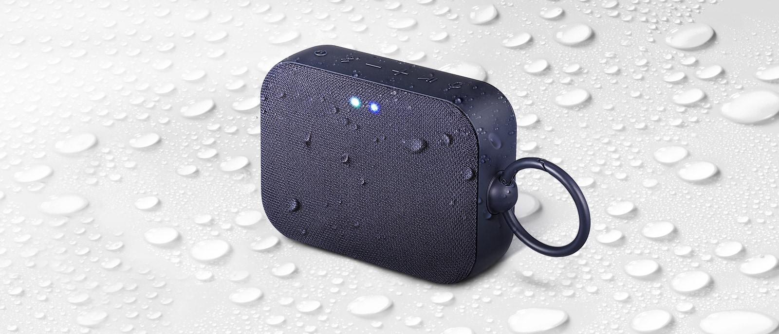 Sobre un fondo blanco, LG XBOOM Go PM1 con vista hacia la izquierda.  Hay gotas de agua sobre y debajo de LG XBOOM Go PM1.