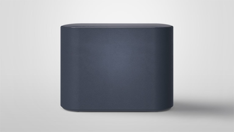 Un subwoofer se coloca sobre un piso blanco. La escena cambia para enfocar dos componentes dentro del subwoofer que están vibrando levemente y efectos de ondas de sonido que salen de los dos componentes. La escena cambia para alejarse una vez más y mostrar el exterior de un subwoofer.