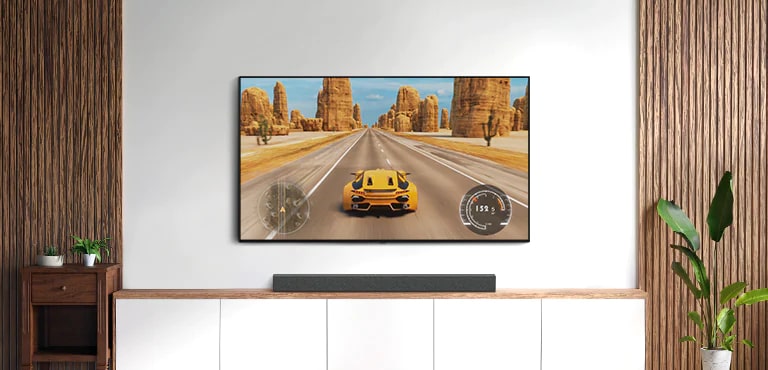 Hay TV y una barra de sonido en una sala de estar. Un juego de carreras de coches está en una pantalla de televisión. (reproducir el video)