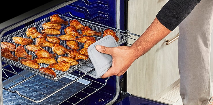 La imágen de abrir el horno y sacar una ala de pollo bien cocida.