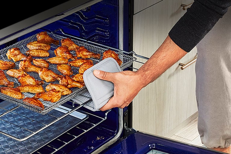 La imágen de abrir el horno y sacar una ala de pollo bien cocida.