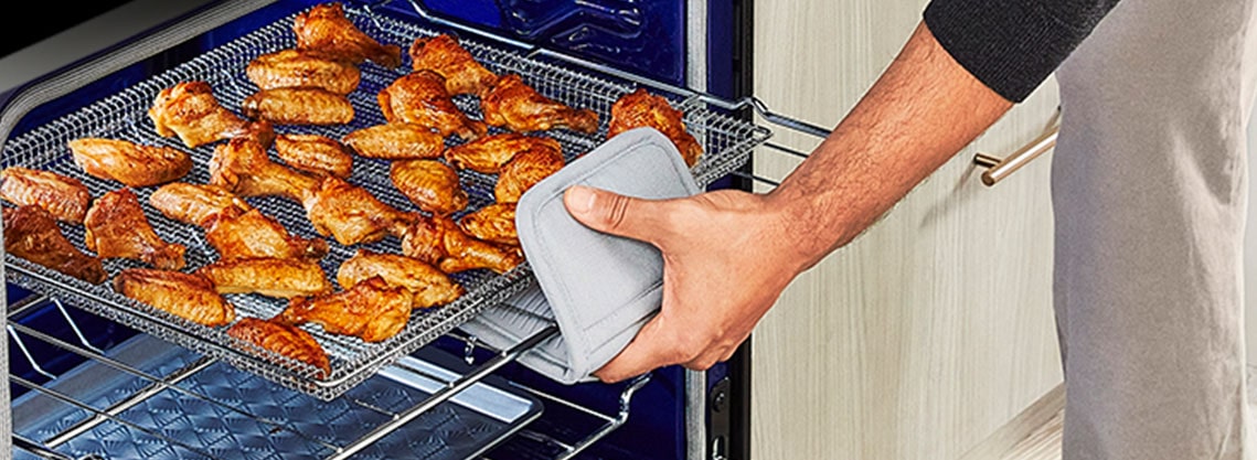 La imágen de abrir el horno y sacar una ala de pollo bien cocida.