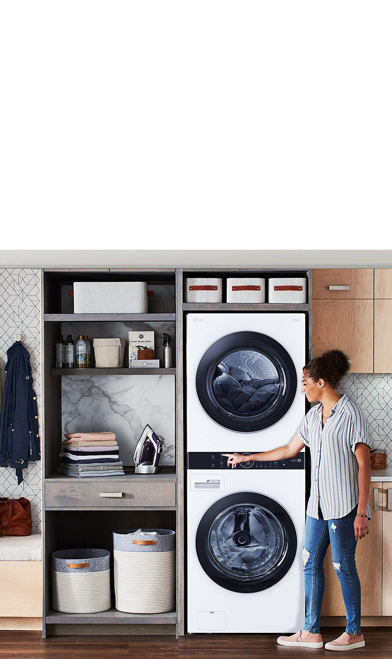 Una Torre de Lavado LG negra se instala en una lavandería, y una mujer se inclina para apretar un botón de la máquina.