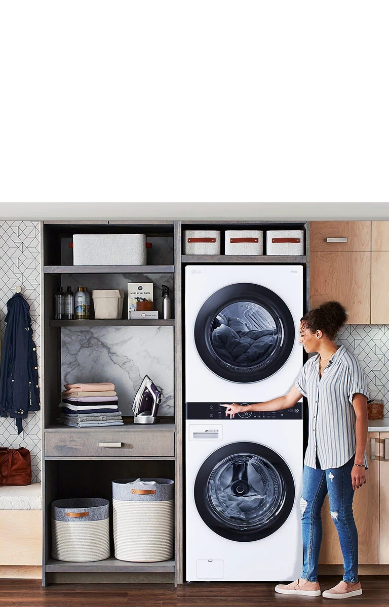 Una Torre de Lavado LG negra se instala en una lavandería, y una mujer se inclina para apretar un botón de la máquina.