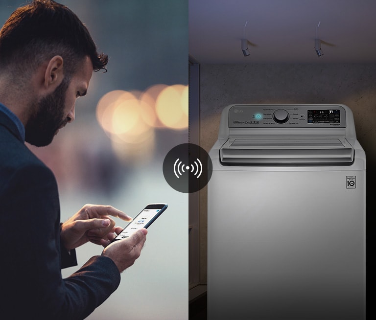 Un hombre controla el estado de la lavadora a través de una aplicación de teléfono móvil.