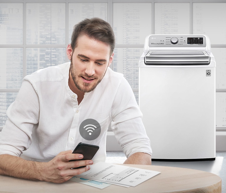 Un hombre controla el estado de la lavadora a través de una aplicación de teléfono móvil.