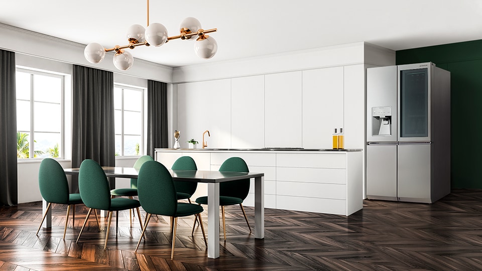 El refrigerador LG SIGNATURE se coloca en el lado derecho de la casa y una mesa de cocina con varias sillas verdes en el lado izquierdo.