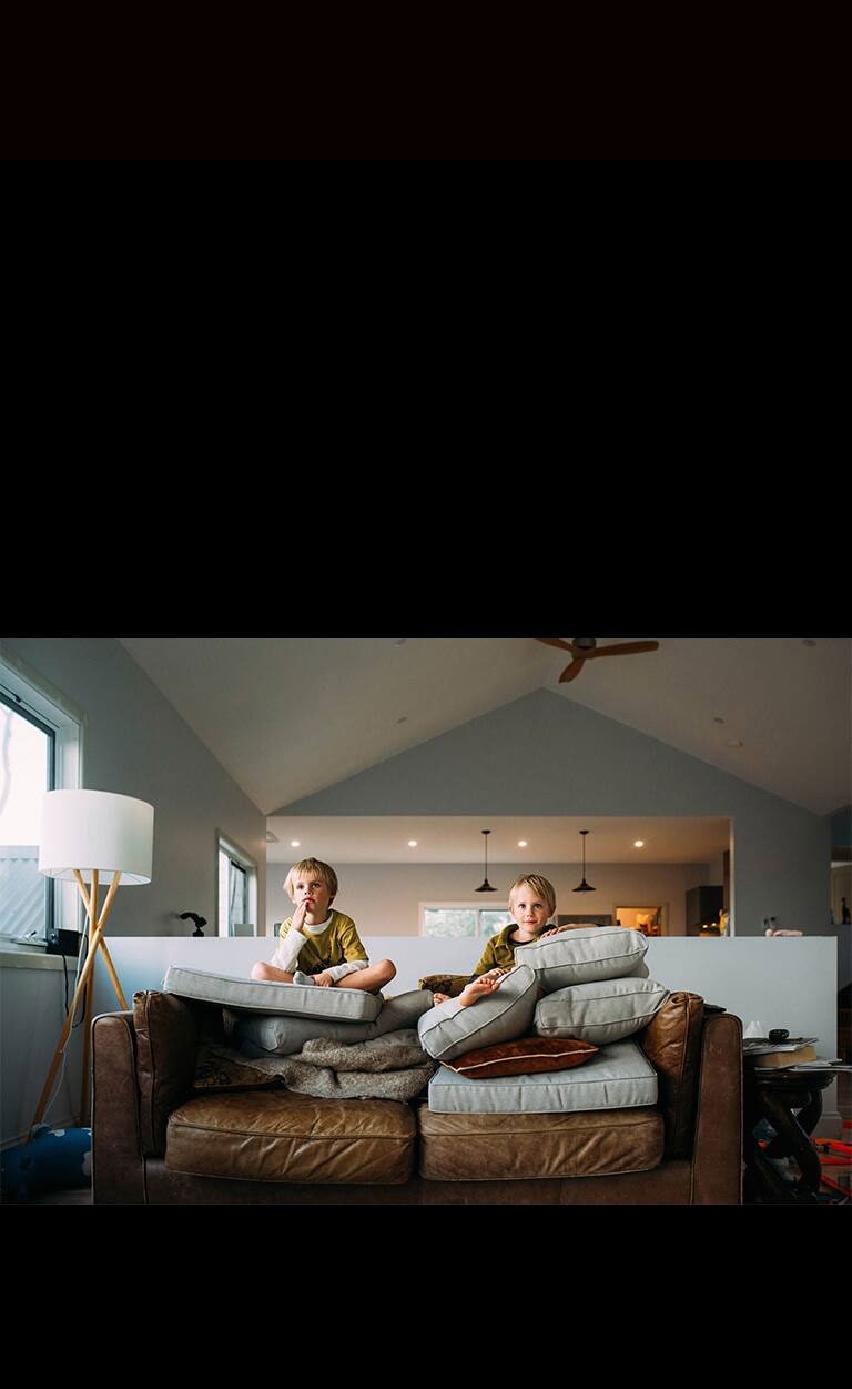 Dos gemelos miran algo sentados en un sofá.