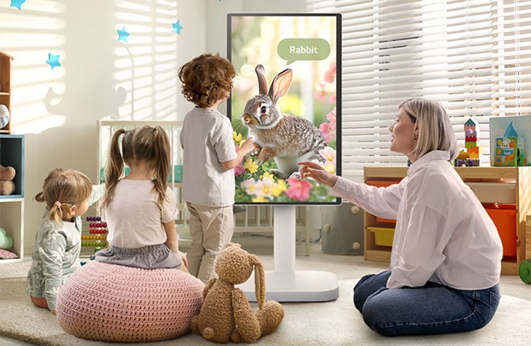 Esta imagen muestra a una mujer y tres niños jugando usando un LG Smart Monitor Swing.