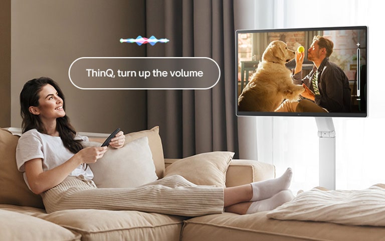 Una mujer está subiendo el volumen del LG Smart Monitor Swing usando un Magic Remote.