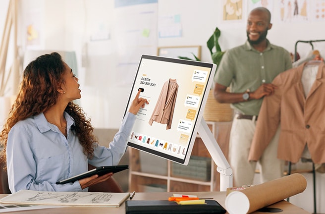 Un hombre sostiene una chaqueta, mientras que una mujer toca la pantalla del LG Smart Monitor Swing para ver la información.