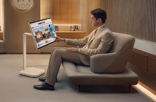 Un hombre en el salón VIP está leyendo las noticias en un LG Smart Monitor Swing.