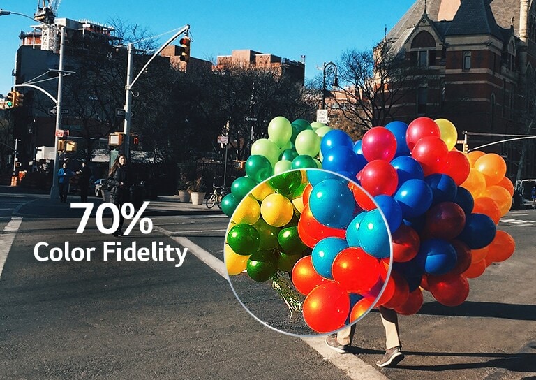 Una parte de un montón de globos de colores que un hombre sujeta mientras cruza el paso de peatones se agranda para mostrar el efecto de la fidelidad del color. (reproducir el vídeo)
