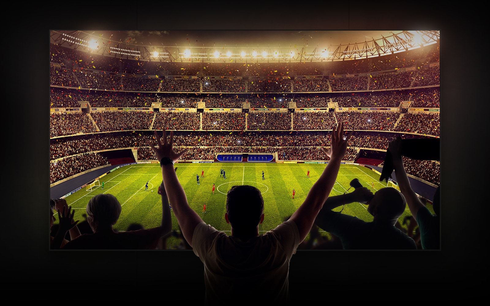 Four people sitting on a couch watching a large screen TV displaying a soccer stadium filled with spectators.