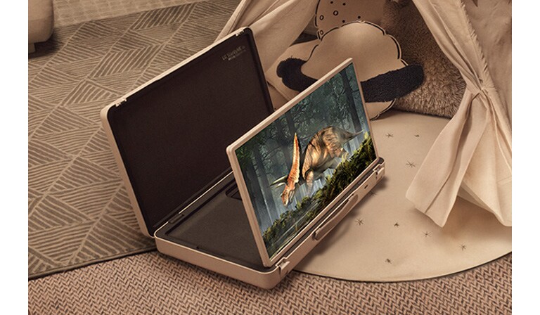 El estuche de la televisión LG StanbyME Go está abierto y la pantalla está desplegada. Dos niños en casa en un campamento improvisado con una tienda y luces cálidas y acogedoras. Están viendo un video en la pantalla de la StanbyME Go.