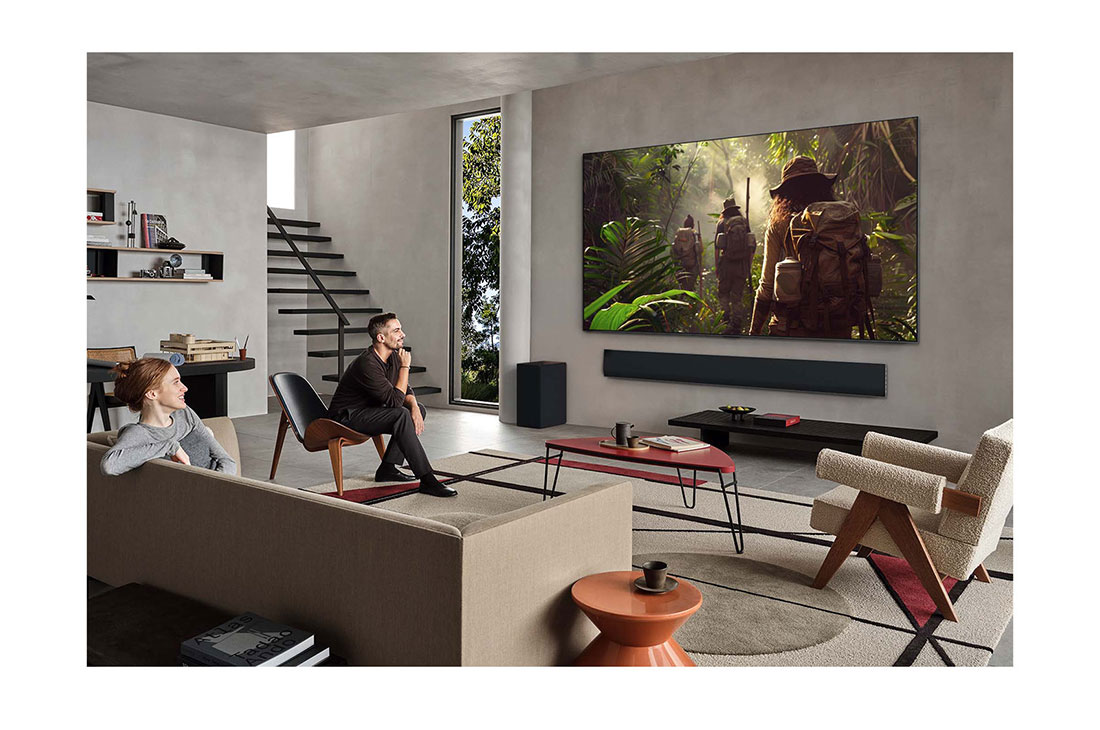LG 77 pulgadas LG OLED evo AI G5 4K Smart TV 2025, Wide view of a living room inside a premium home, a man is watching a movie on his wall-mounted LG OLED TV. The TV's design blends elegantly with the wall and the interior design., OLED77G5PSA, thumbnail 13