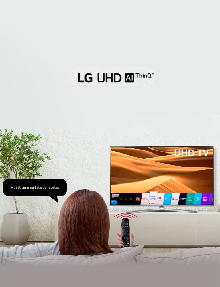 Una mujer sentada en us sofá utiliza el Google Assistant de un TV LG UHD con su Magic Remote.