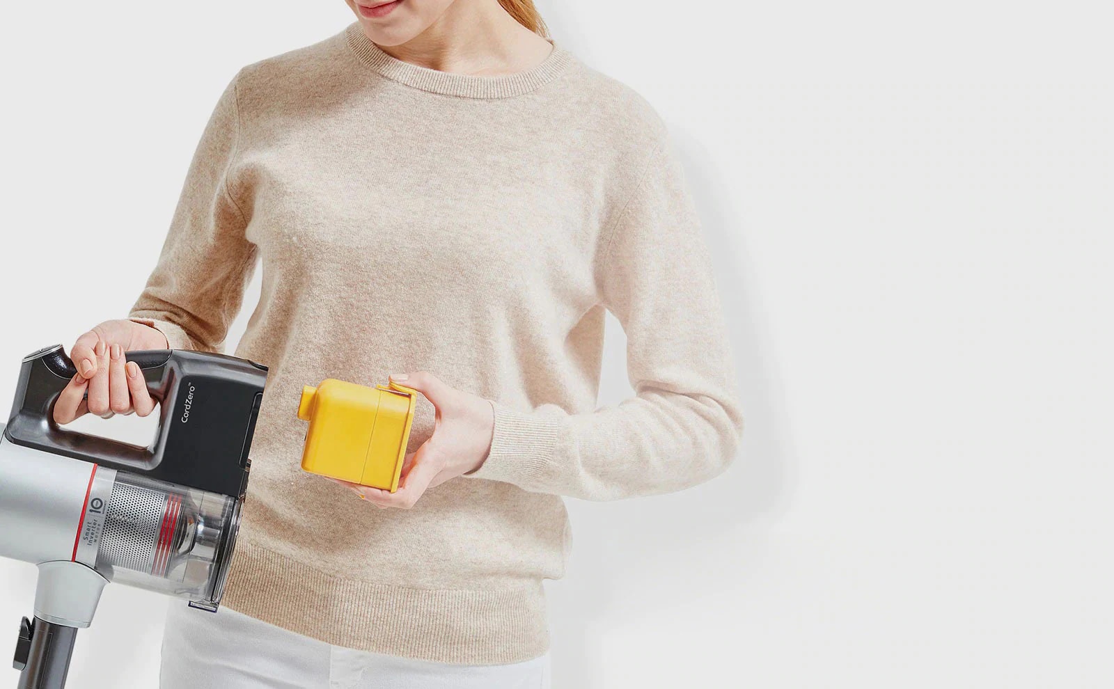 Mujer coloca la batería recargable en la aspiradora LG CordZero™ A9 para un rendimiento de hasta 50 minutos.
