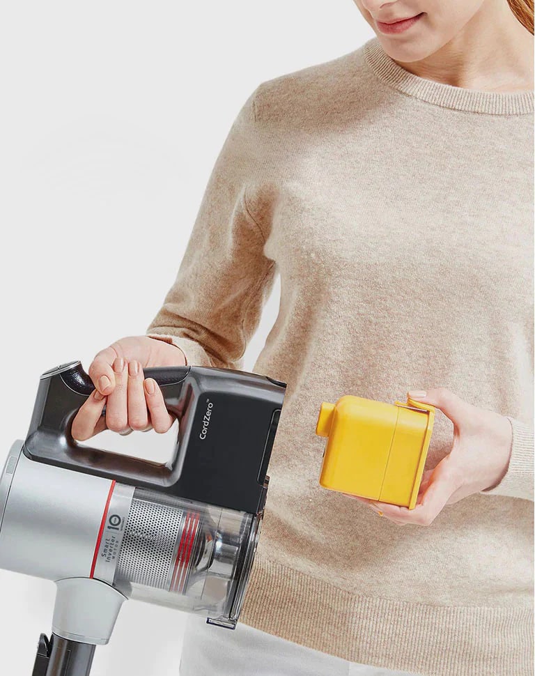Mujer coloca la batería recargable en la aspiradora LG CordZero™ A9 para un rendimiento de hasta 50 minutos.
