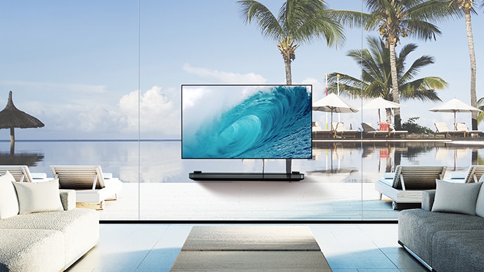 LG SIGNATURE OLED TV W躺在客厅里，窗外展示着蓝色的海景，在屏幕上显示凉爽的波浪。