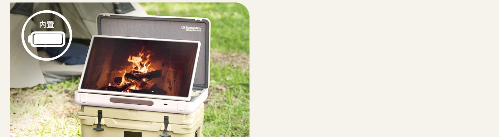 The LG StanbyME Go is placed in front of a tent, and the screen displays one of the relaxing themes--a fireplace. On the left top corner, built-in battery icon is shown.