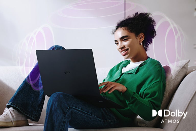 A person sitting on a couch, enjoying immersive audio while using an LG gram laptop. The text highlights Dolby Atmos technology, emphasizing a rich, expansive, 360-degree auditory experience. Surrounding sound waves in the background visually represent the immersive soundscape.	