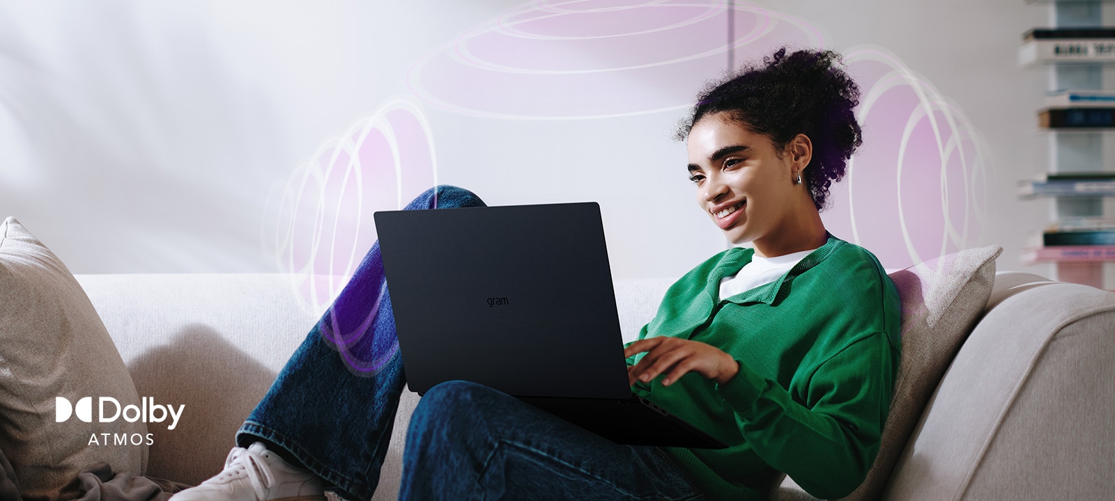 A person sitting on a couch, enjoying immersive audio while using an LG gram laptop. The text highlights Dolby Atmos technology, emphasizing a rich, expansive, 360-degree auditory experience. Surrounding sound waves in the background visually represent the immersive soundscape.	