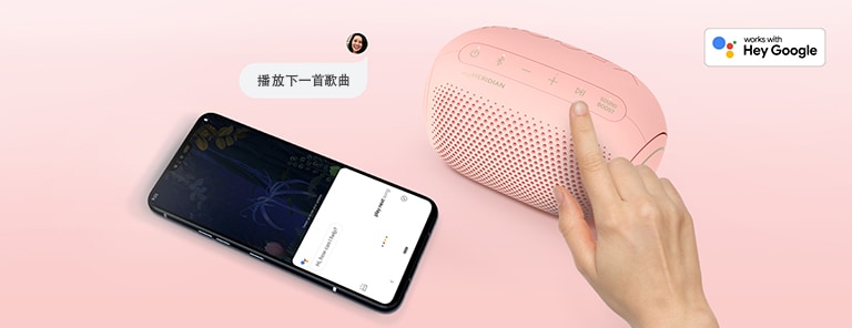 一只手按下 LG XBOOM Go 上的按钮。它的旁边有一部智能手机。有一个语音气泡。右上方是 Google 的标志。