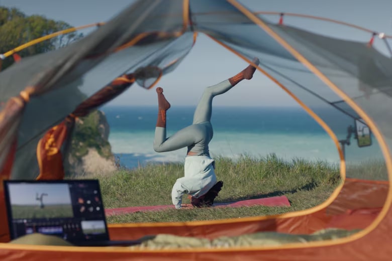 一位女士在海边的瑜珈垫上做头倒立，用 LG gram 上显示的智能型手机拍摄。