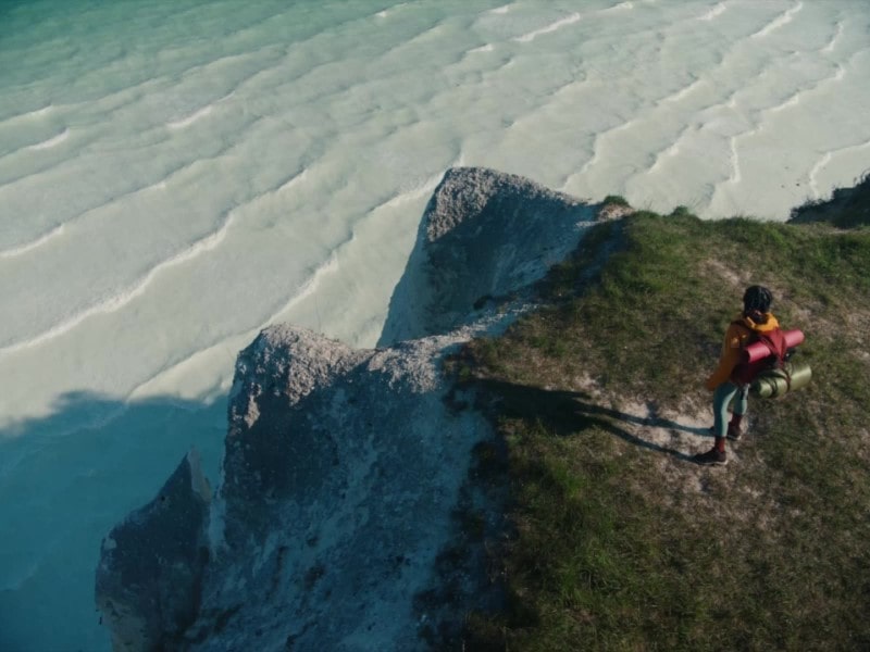 一名妇女将行李放在俯瞰大海的悬崖上。她用智能型手机拍摄自己做瑜伽的视频，在 LG gram 上编辑视频，满意地微笑，然后毫不费力地将轻巧的 LG gram 放入包中。