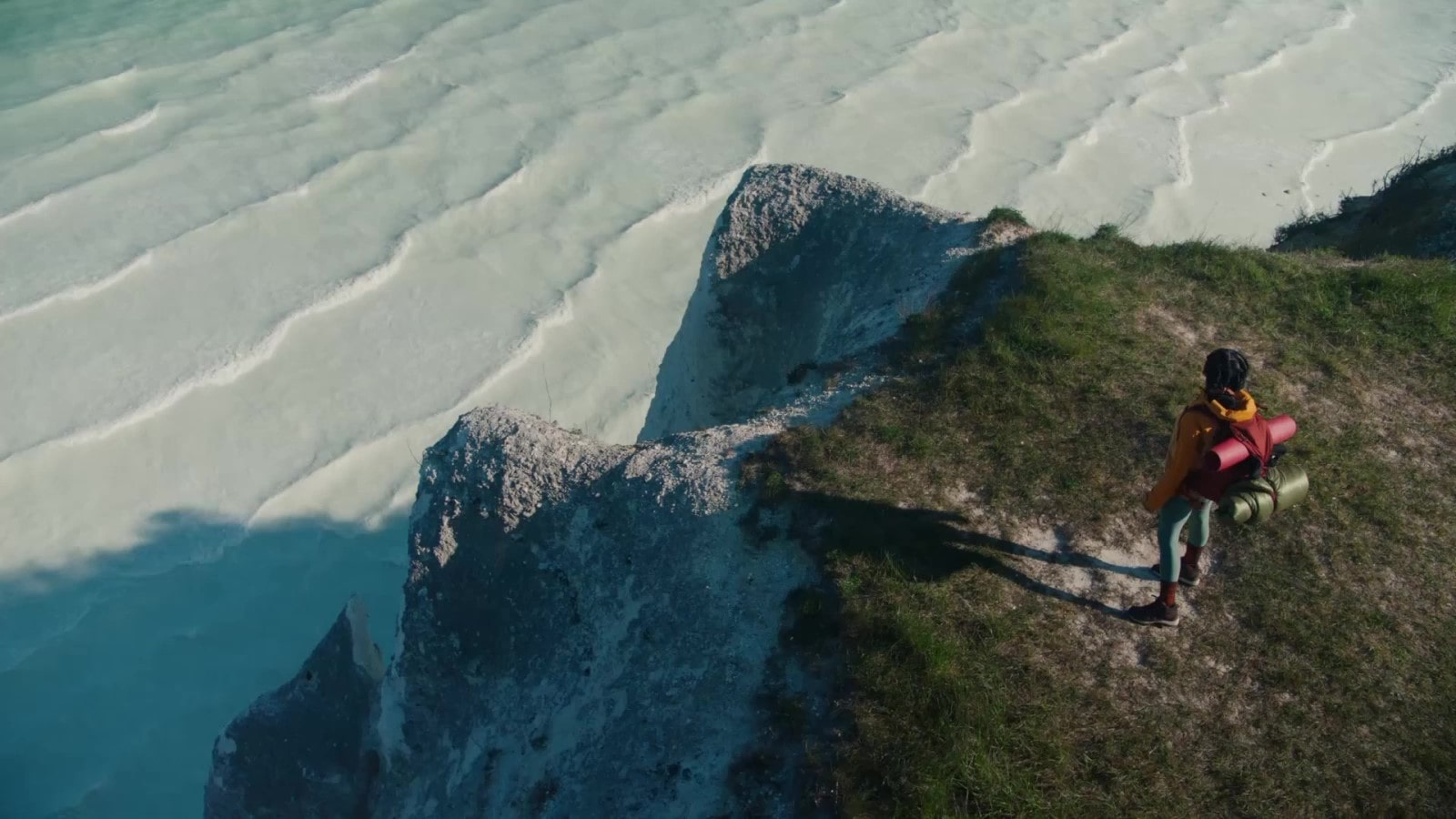 一名妇女将行李放在俯瞰大海的悬崖上。她用智能型手机拍摄自己做瑜伽的视频，在 LG gram 上编辑视频，满意地微笑，然后毫不费力地将轻巧的 LG gram 放入包中。