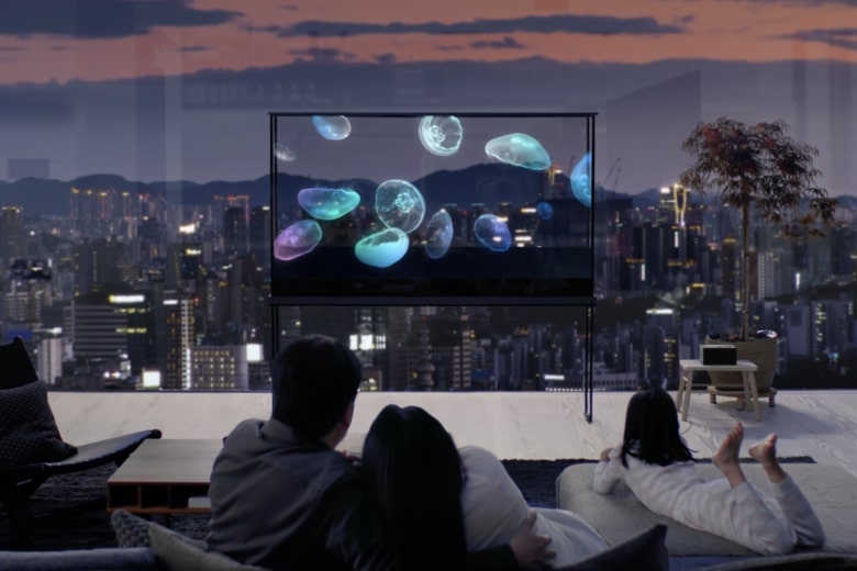 一家人正在享受一台 LG Oled T，上面漂浮着一只水母，而城市景观则透过透明屏幕映入眼帘。