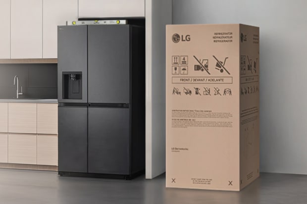 Geladeira LG preta posicionada à esquerda, com uma caixa de instalação colocada à direita, encostada na parede.