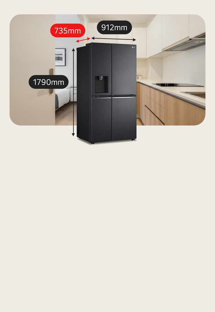 Geladeira LG preta de tamanho médio com dispenser de água. Atrás, uma cama à esquerda e uma cozinha com um fogão de indução à direita.