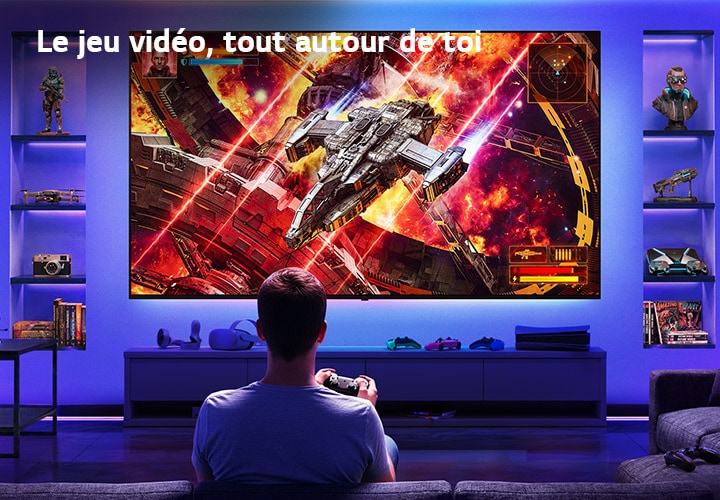 Le téléviseur LG Ultra Big est monté au mur dans une salle de jeux éclairée au néon, où un grand écran montre une scène de bataille spatiale vivante alors qu’un joueur fait face à l’écran, illustrant une expérience de jeu immersive et captivante.
