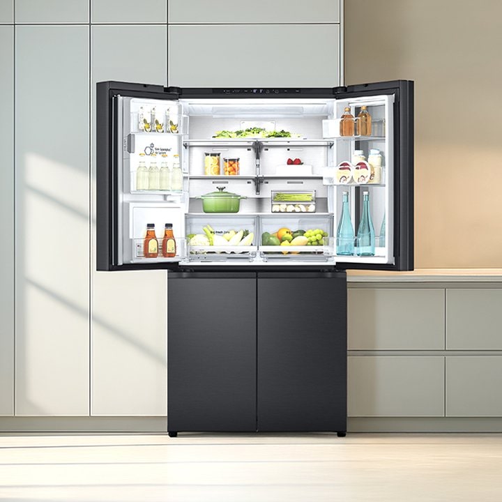 Refrigerador LG abierto en cocina moderna, lleno de bebidas, frutas y verduras, destaca por su almacenamiento limpio y organizado.