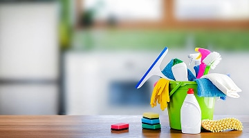 Productos de limpieza como guantes, esponjas, cepillos y paños sobre mesa, esenciales para mantener un refrigerador LG fresco y limpio.