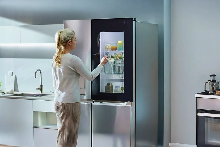 Mujer usa refrigerador LG con panel InstaView, viendo el interior sin abrir la puerta para ahorrar energía y mantener frescura.
