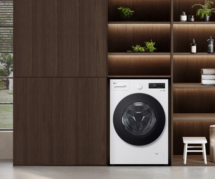 Lavadora LG instalada en una moderna lavandería con estantes de madera y luz natural que entra por una gran ventana.