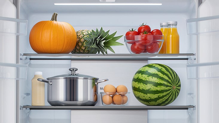 Ablagen aus gehärtetem Glas in einem Kühlschrank, auf denen sich zur Veranschaulichung der Strapazierfähigkeit schwere Gegenstände wie ein Topf und eine Wassermelone befinden