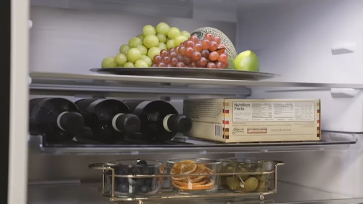 Innenraum des LG Kühl-/Gefrierschranks mit Weinregal, in dem Flaschen neben frischen Lebensmitteln aufbewahrt werden.