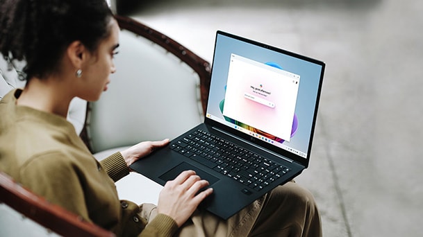 Dieses Bild zeigt eine Person, die einen Laptop nutzt. Der Bildschirm des Laptops zeigt eine farbenfrohe Benutzeroberfläche mit einer Meldung zur längeren Akkulaufzeit.