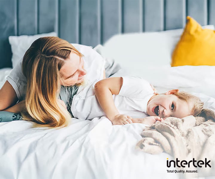 Mother and child lying on a clean white bed enjoying bedding washed with LG washing machine’s Steam Power technology