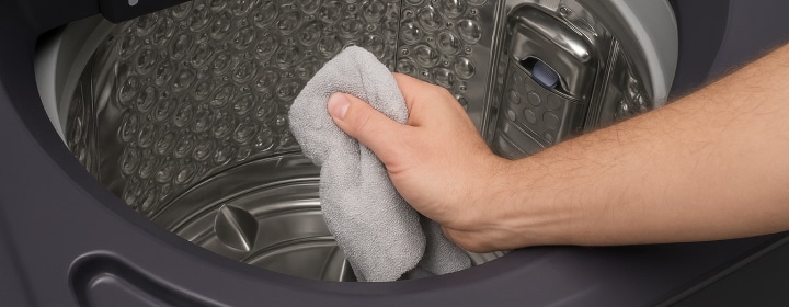 LG front load washing machine drum being wiped with a soft cloth showing easy maintenance for hygienic washing performance	
